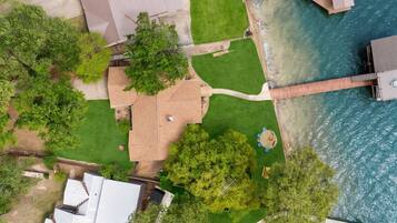 An aerial view of a residential property with a swimming pool, a wooden deck, and a grassy lawn.