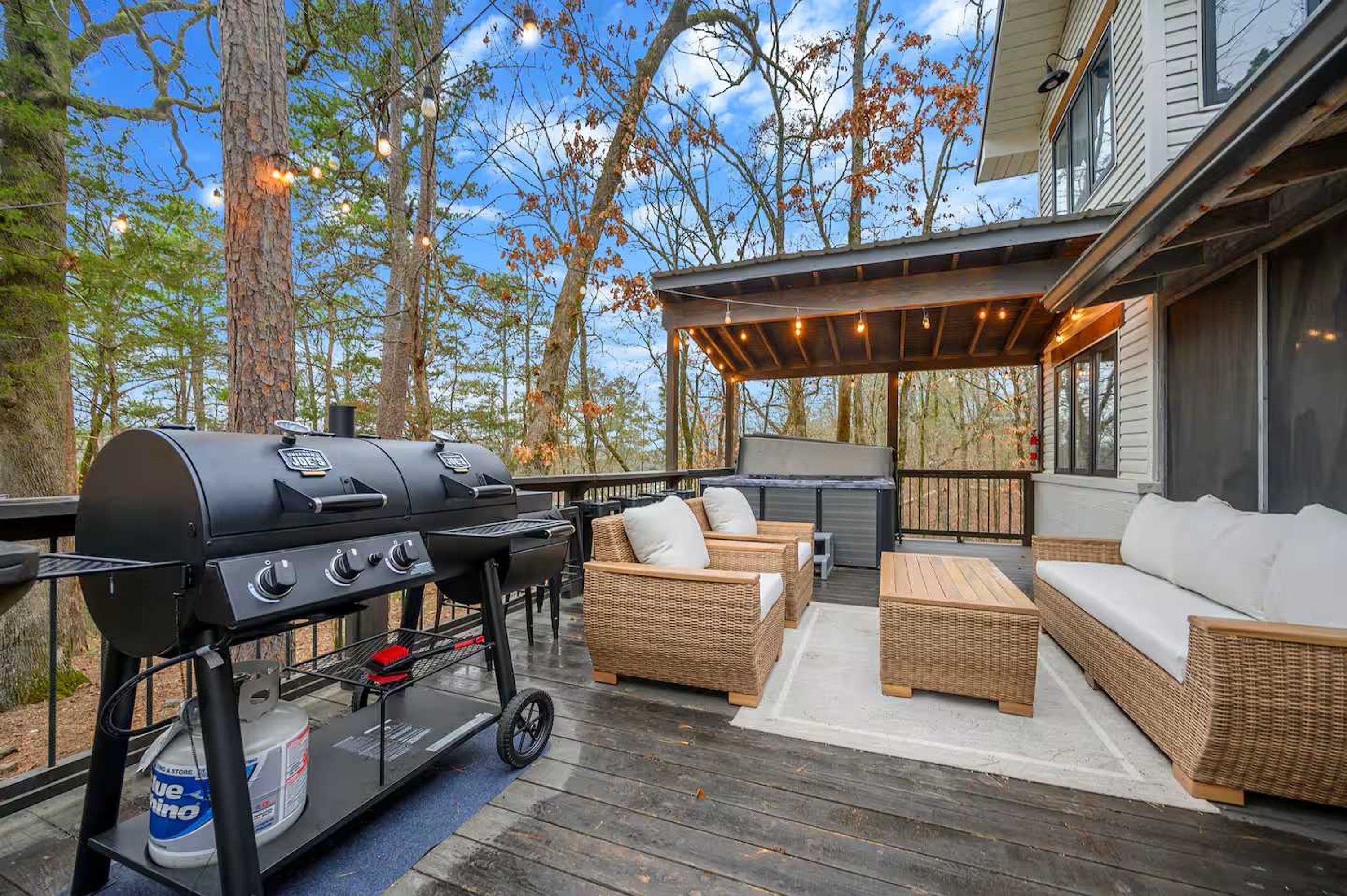 Une terrasse extérieure équipée d’un barbecue, de meubles en osier et d’un espace salon abrité.