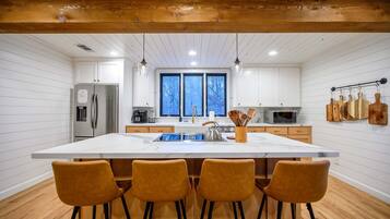 A modern kitchen with a large island, stainless steel appliances, and wooden bar stools.