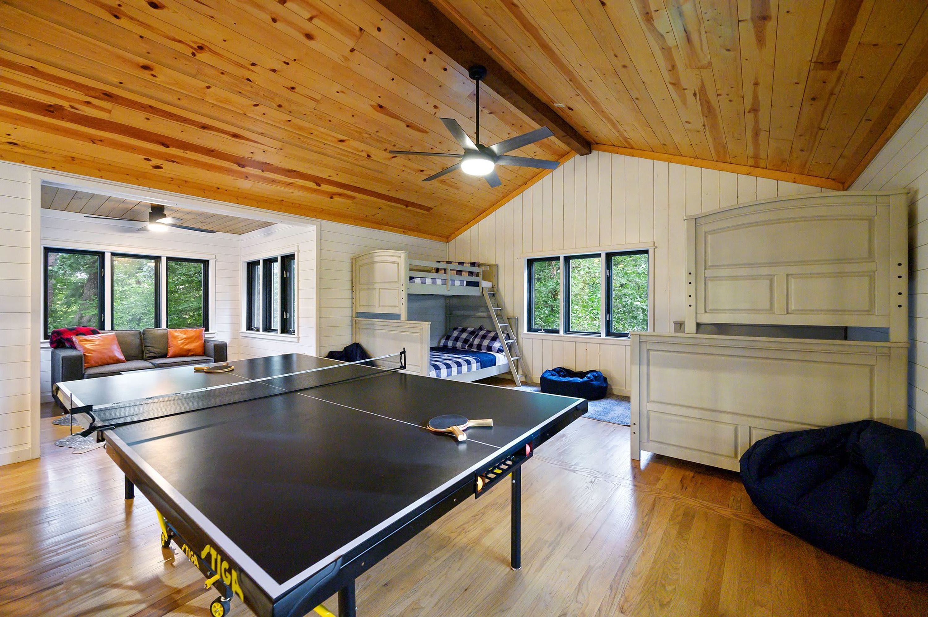 A room with a ping pong table, a bunk bed, and a ceiling fan.