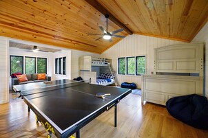 A room with a ping pong table, a bunk bed, and a ceiling fan.