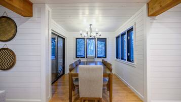 A dining area with a long wooden table, chairs, and a chandelier.