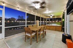 A covered patio area with a dining table and chairs, a hot tub, and a ceiling fan. - Paradise Htd Pool Tiki Bar Hot Tub Games (Seminole)