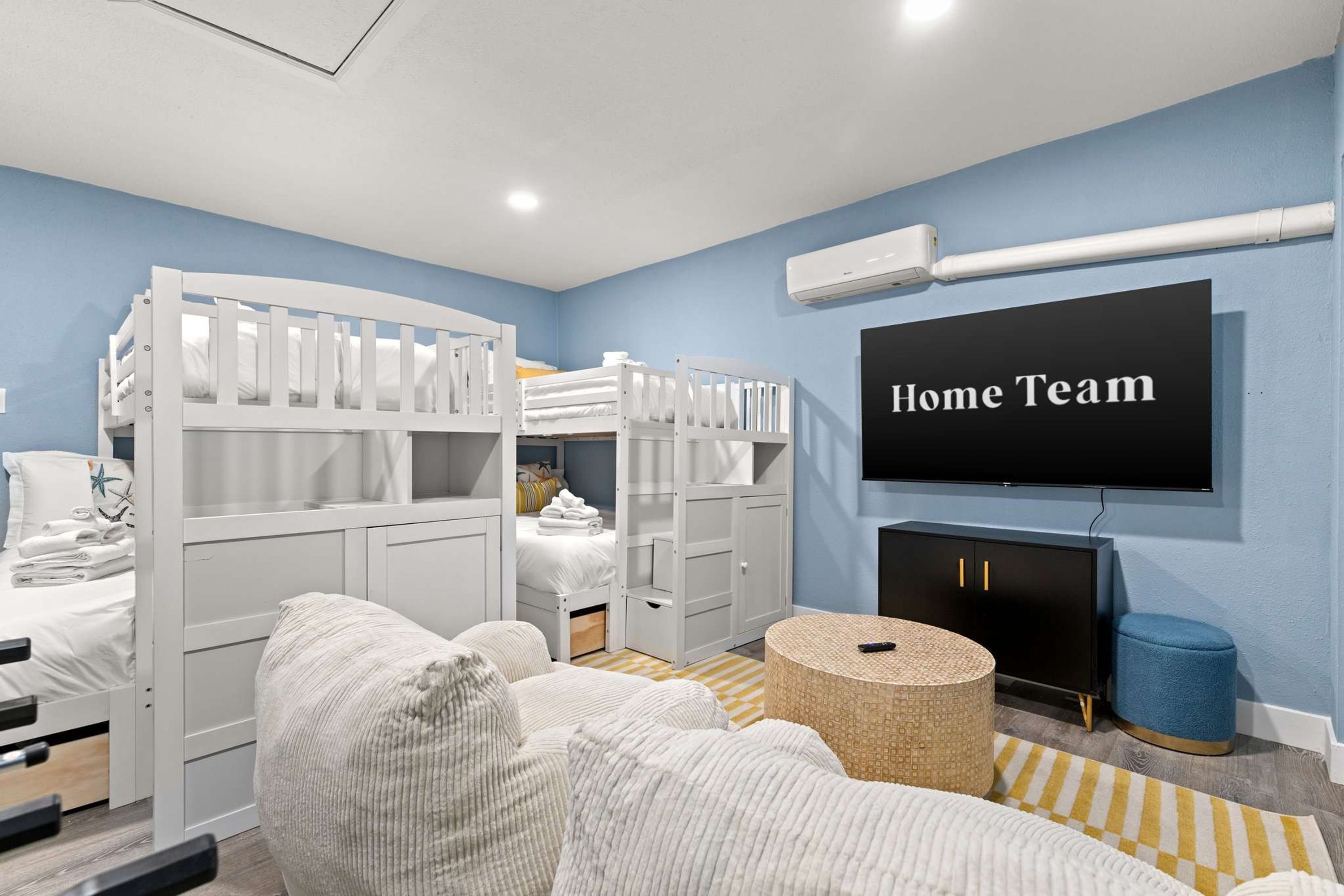 Un dormitorio con literas, televisor, chimenea y un cartel que dice 'Home Team'.