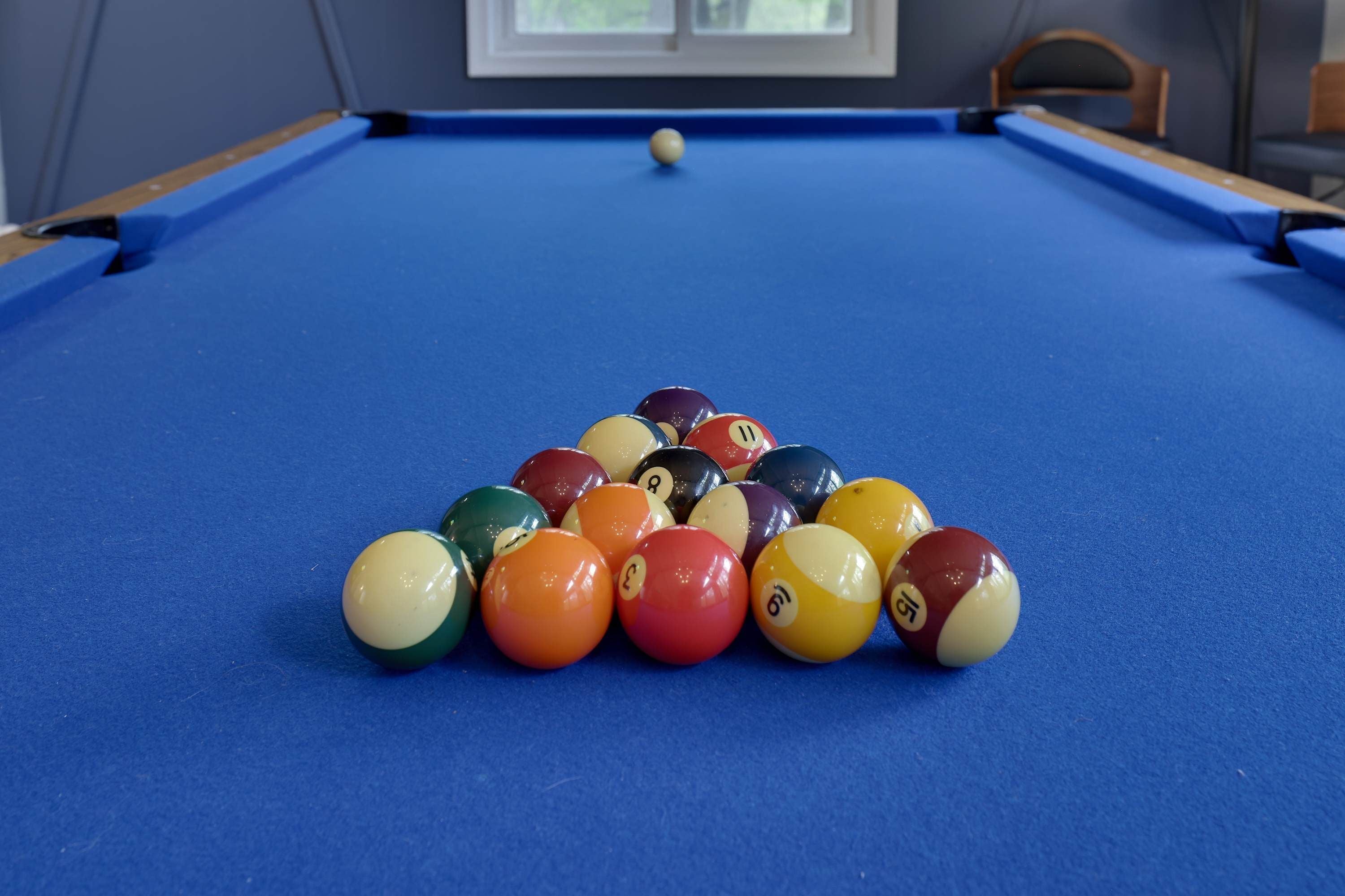 A pool table with a set of billiard balls arranged in a pyramid formation.