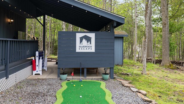 A Bluewood Escape building with a covered entrance, a small patio area, and a signboard. - Bluewood Escape Sauna Hot Tub Game Room (Tobyhanna)