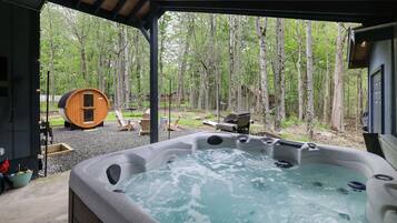 A hot tub area with a wooden deck, surrounded by trees.