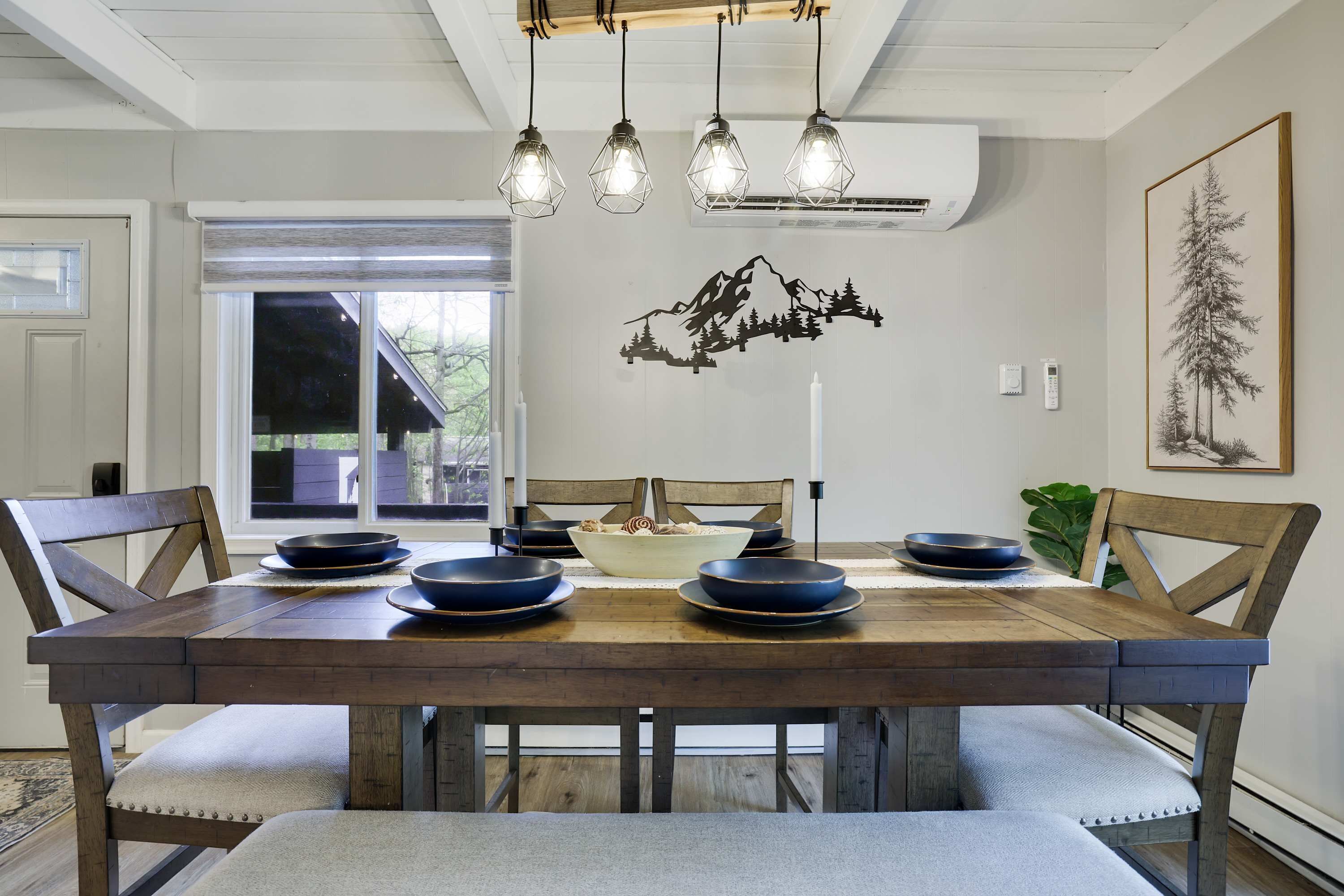 A dining area with a wooden table, chairs, and hanging pendant lights.