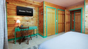 Ein Zimmer mit einem Bett, einem Schreibtisch mit Stuhl, einem Fernseher und einem Kleiderschrank.