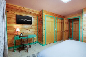 Ein Zimmer mit einem Bett, einem Schreibtisch mit Stuhl, einem Fernseher und einem Kleiderschrank.