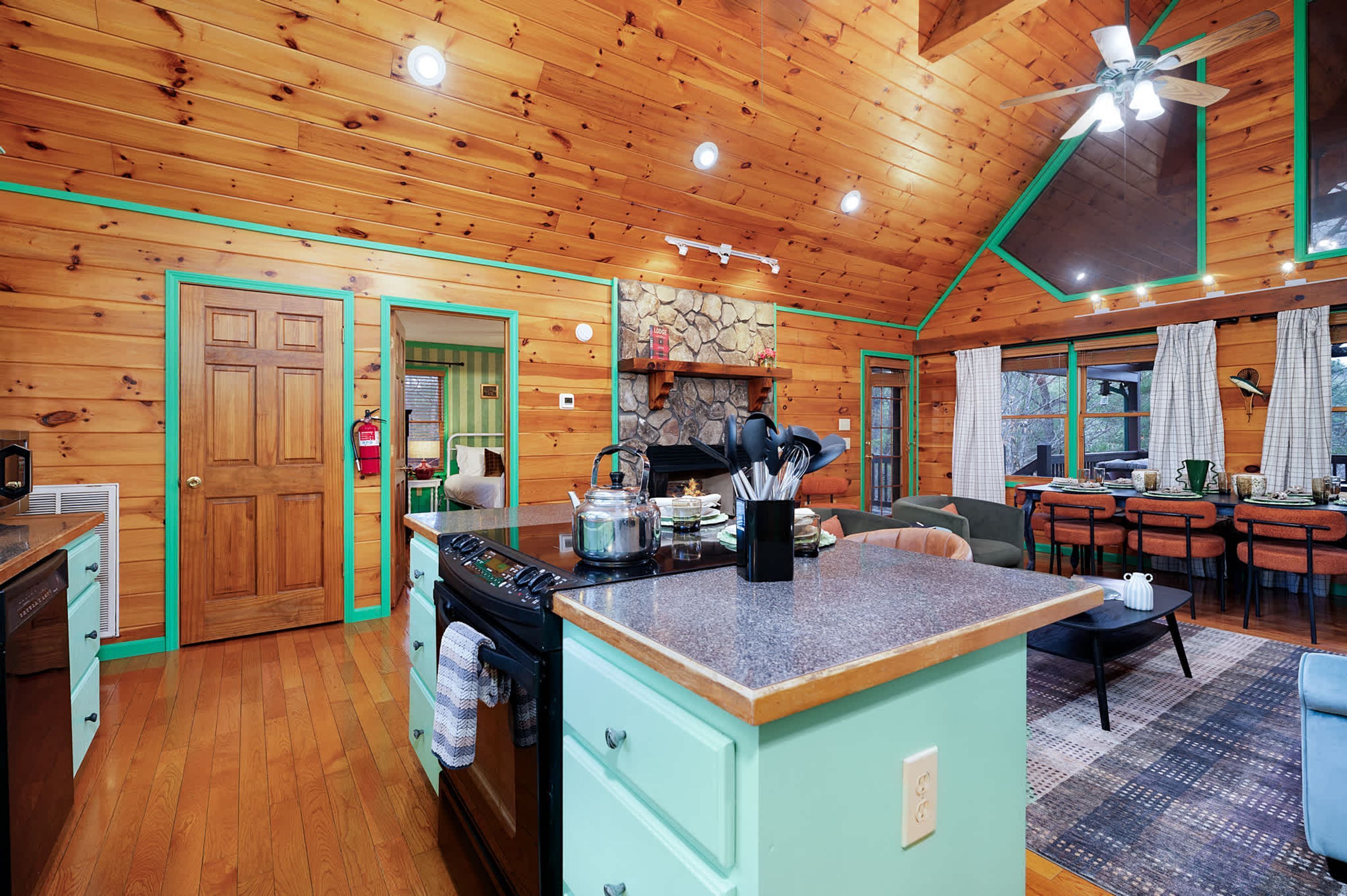 A cozy kitchen with wooden walls, a central island, and a dining area with a table and chairs.