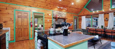 A cozy kitchen with wooden walls, a central island, and a dining area with a table and chairs.