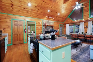 A cozy kitchen with wooden walls, a central island, and a dining area with a table and chairs.