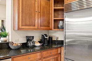 A kitchen with wooden cabinets, a stainless steel refrigerator, a coffee maker, and a black countertop. - Sedona Retreat Pool Hot Tub Mtn Views (Sedona)