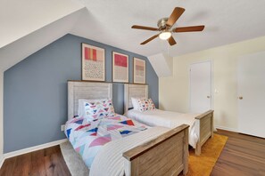 A bedroom with two beds, a ceiling fan, and artwork on the wall. - Savannah Oasis Hot Tub Pickleball Putt Putt (Savannah)