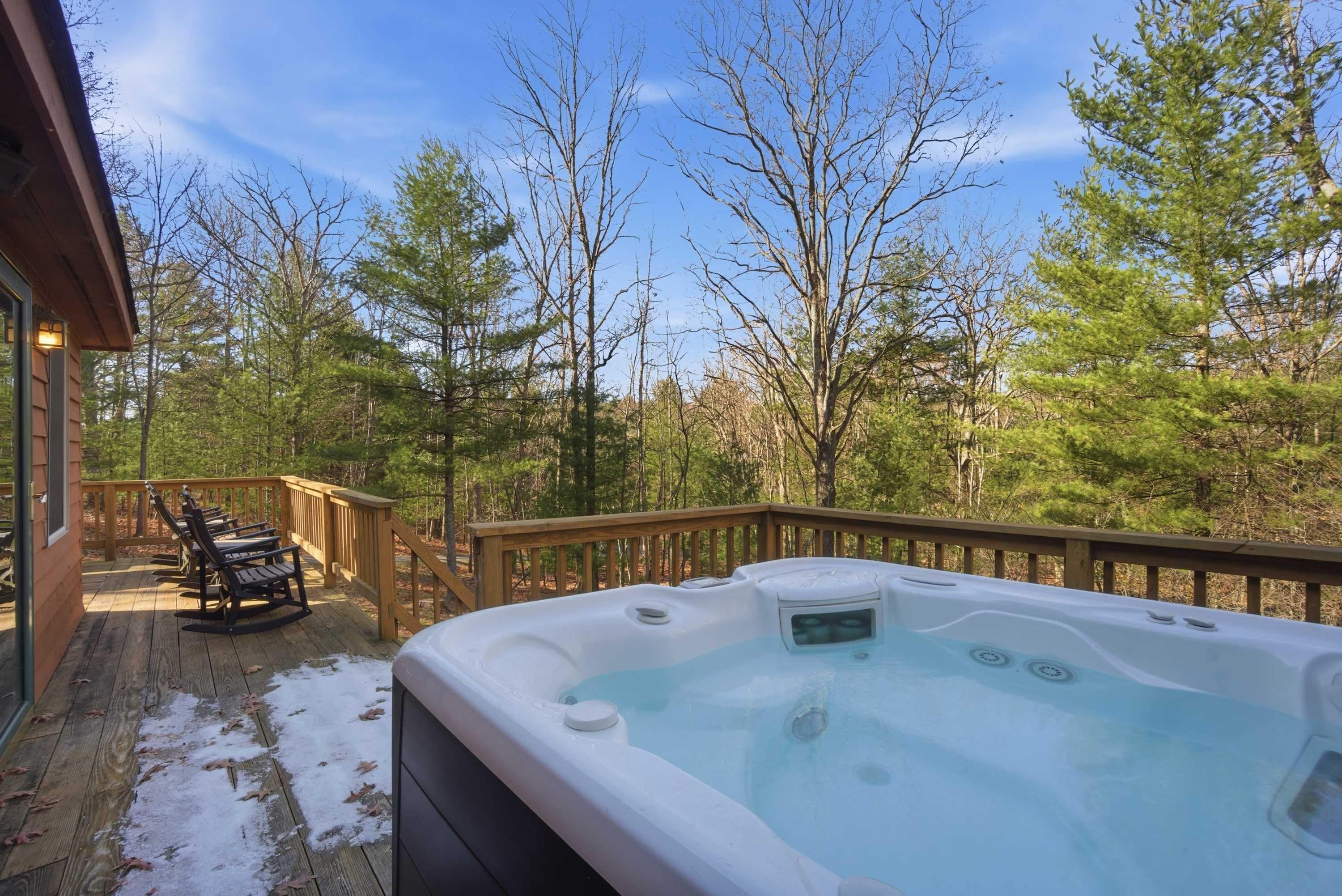 Un jacuzzi en una terraza de madera con vistas a un bosque.