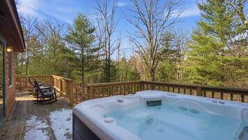 Un jacuzzi en una terraza de madera con vistas a un bosque.
