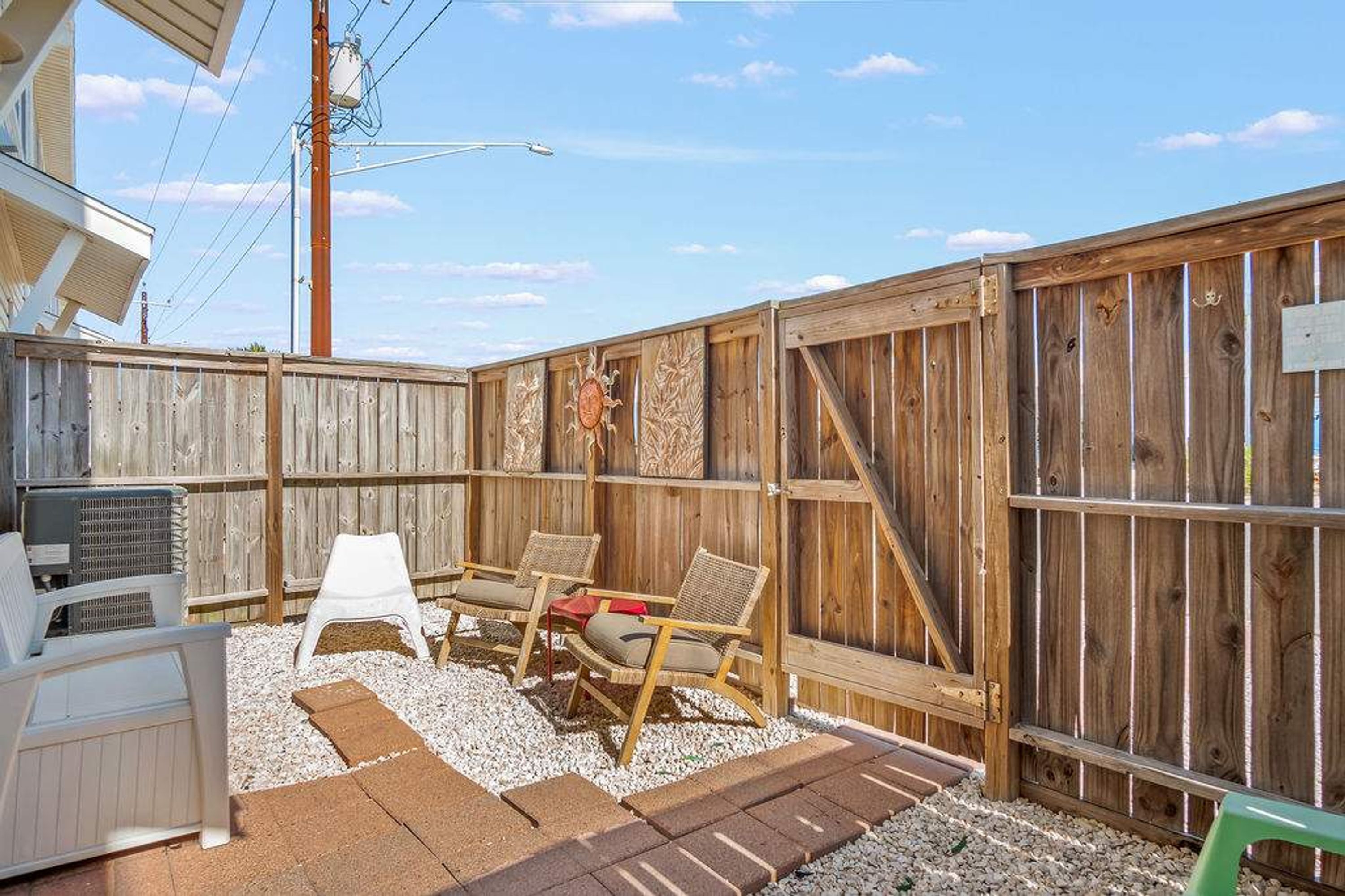 A backyard with a wooden fence, two chairs, a small table, and a grill.