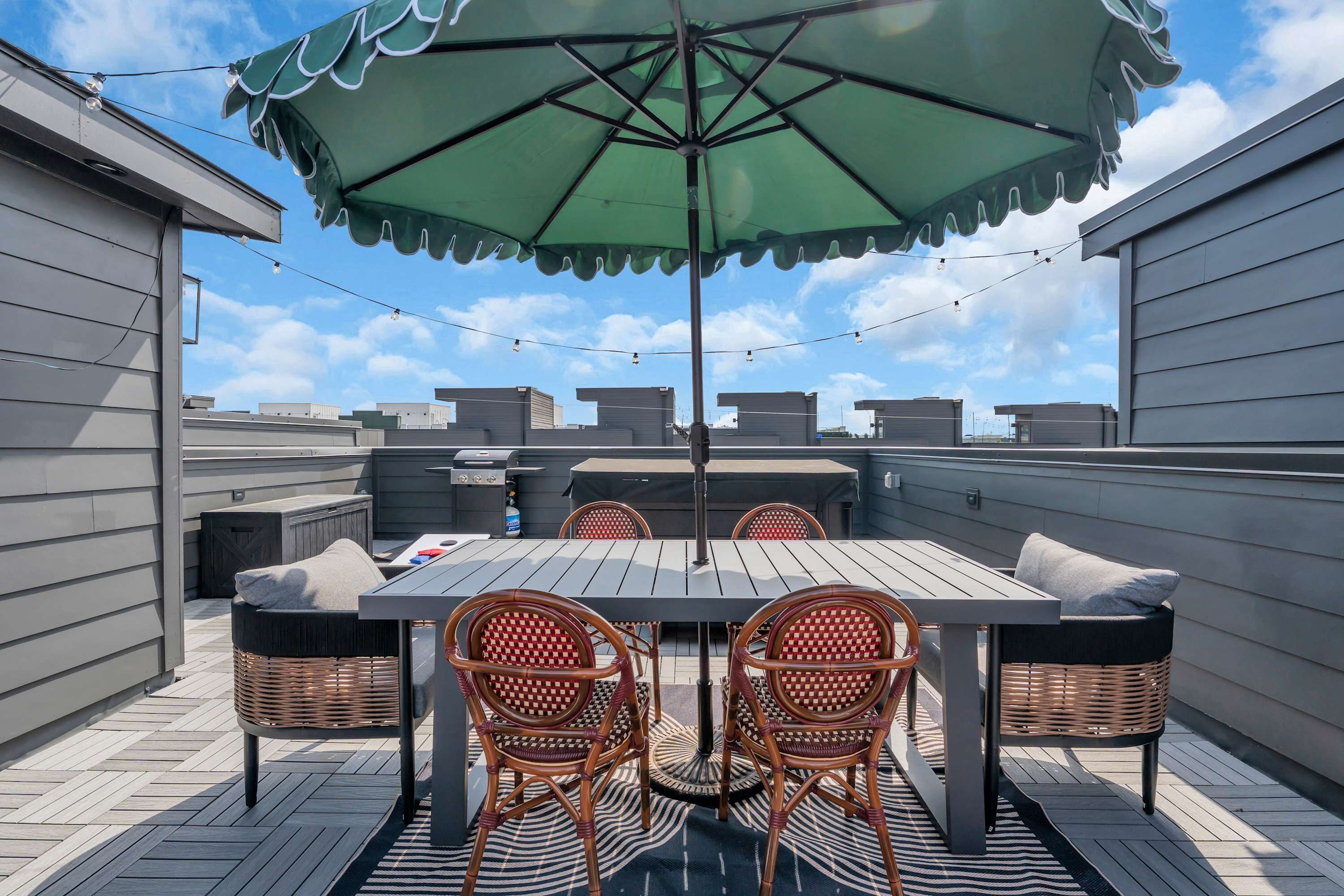 Una terraza en la azotea con una mesa, sillas y un paraguas.