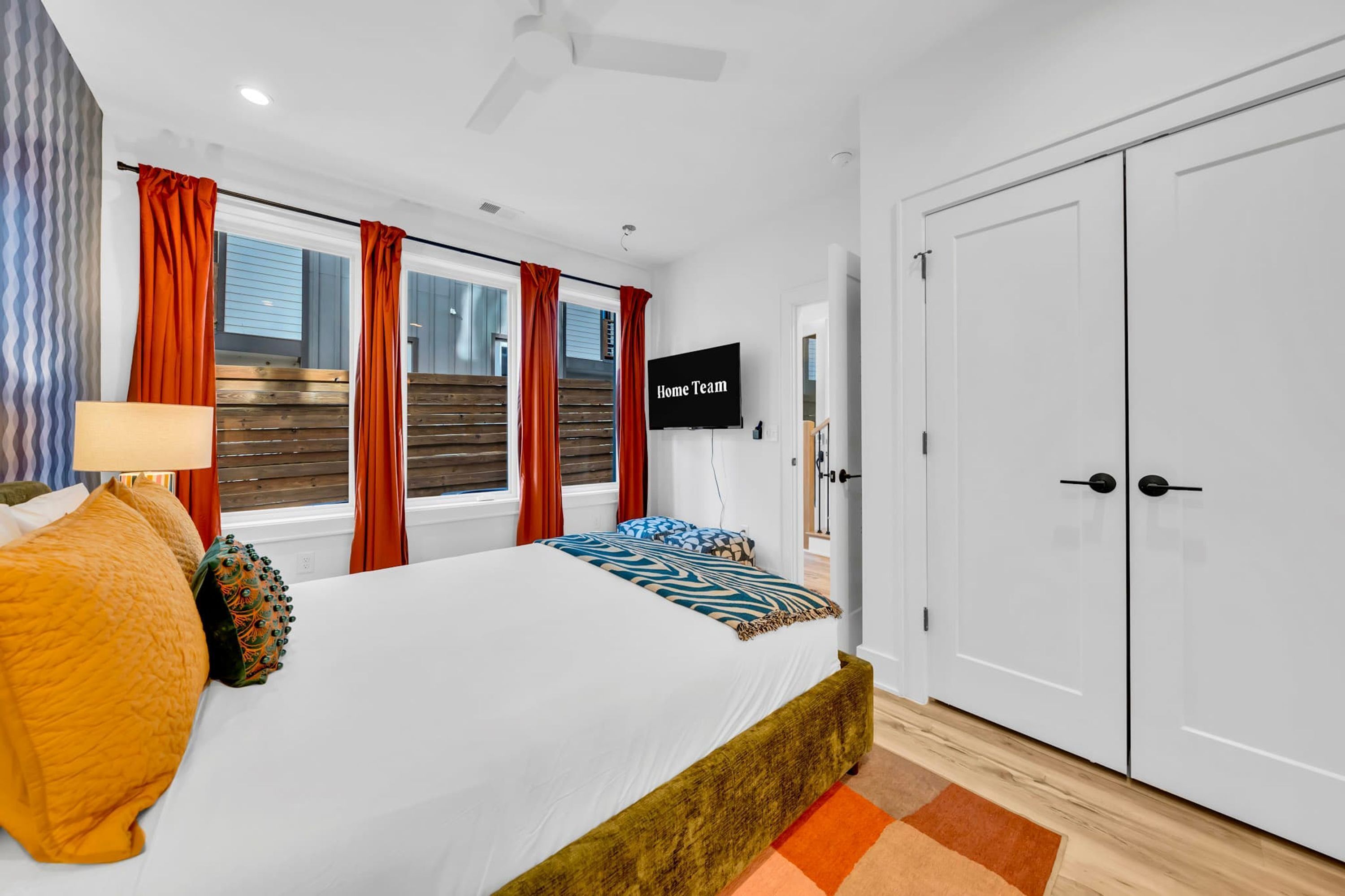 A hotel room with a bed, a TV, a wardrobe, and a window with curtains.