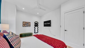 Ein Schlafzimmer mit einem Bett, Kissen, einem an der Wand befestigten Fernseher und einer Tür.