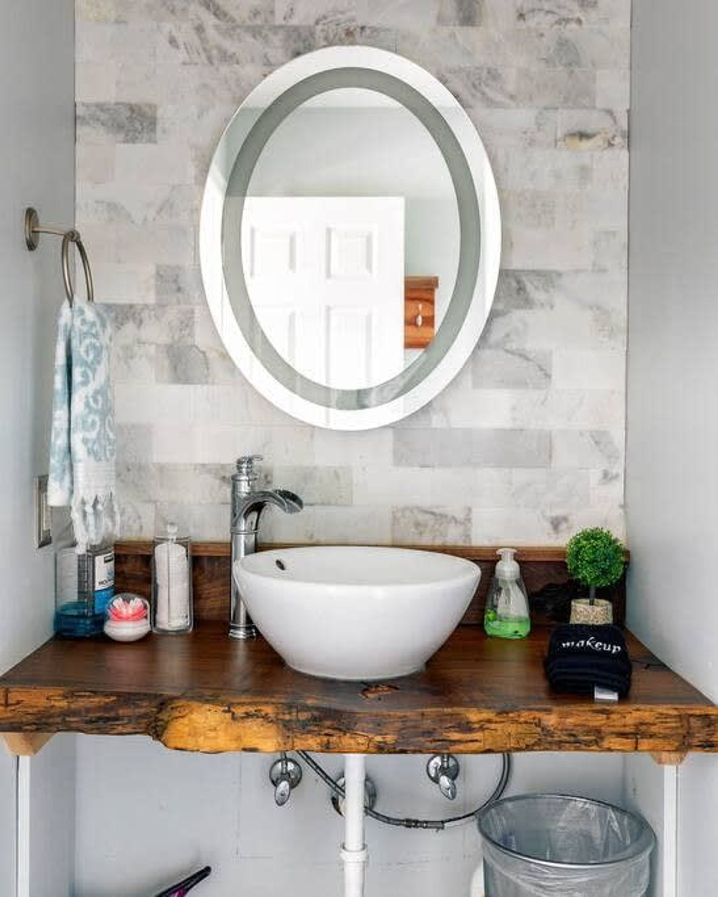 A bathroom with a white sink, a round mirror, and a towel rack.