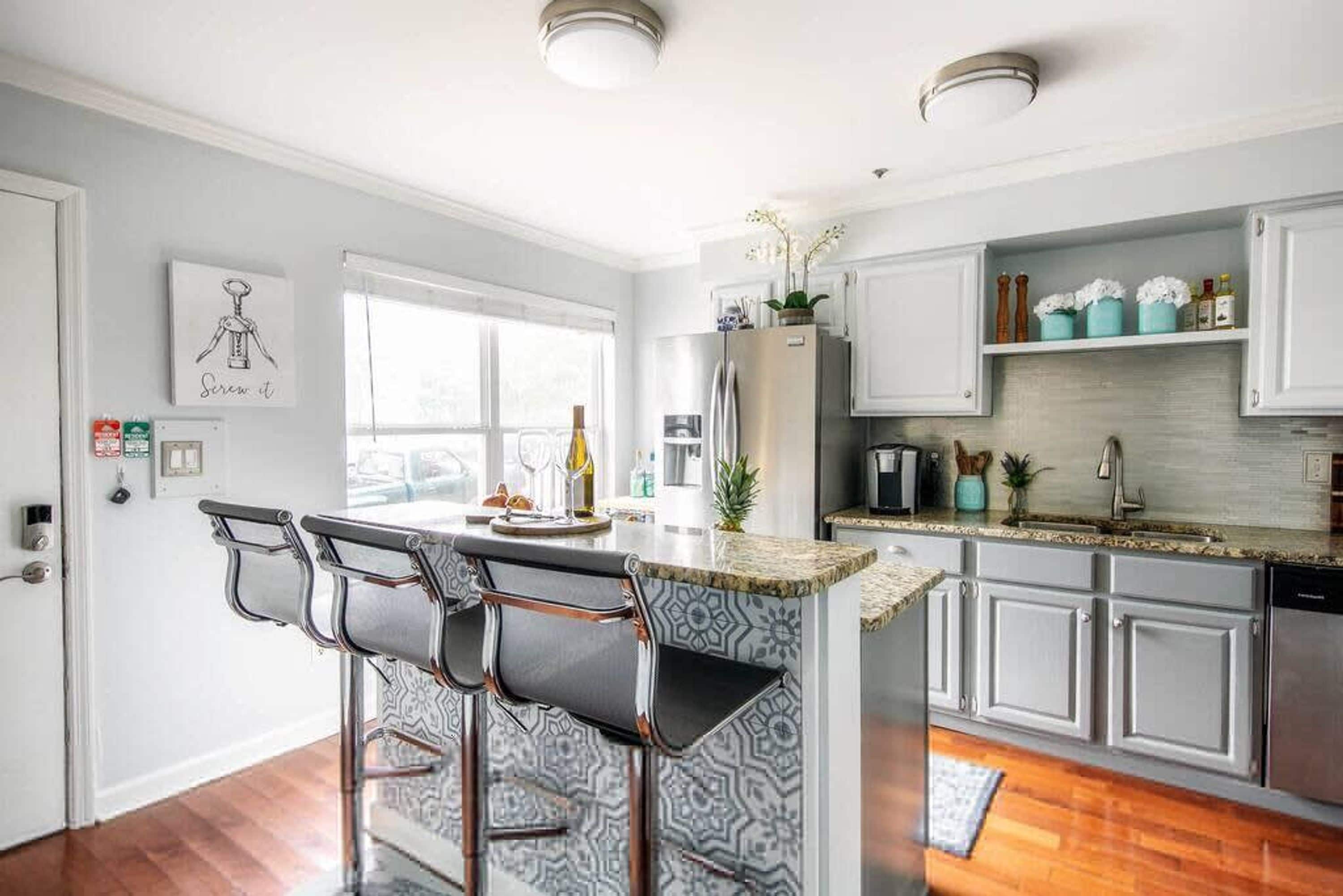 A modern kitchen with a bar area, white cabinetry, and a window providing natural light.