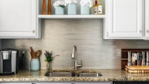 Cocina con gabinetes blancos, lavavajillas de acero inoxidable y encimera de granito.