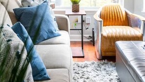 Una sala de estar con sofá, sillón, lámpara y vistas al exterior.