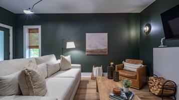 A modern living room with a sofa, a coffee table, a chair, and a painting on the wall.