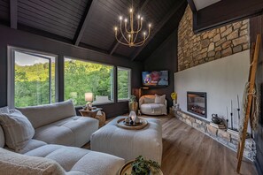 Un salon chaleureux avec une cheminée en pierre, un canapé confortable et un téléviseur.