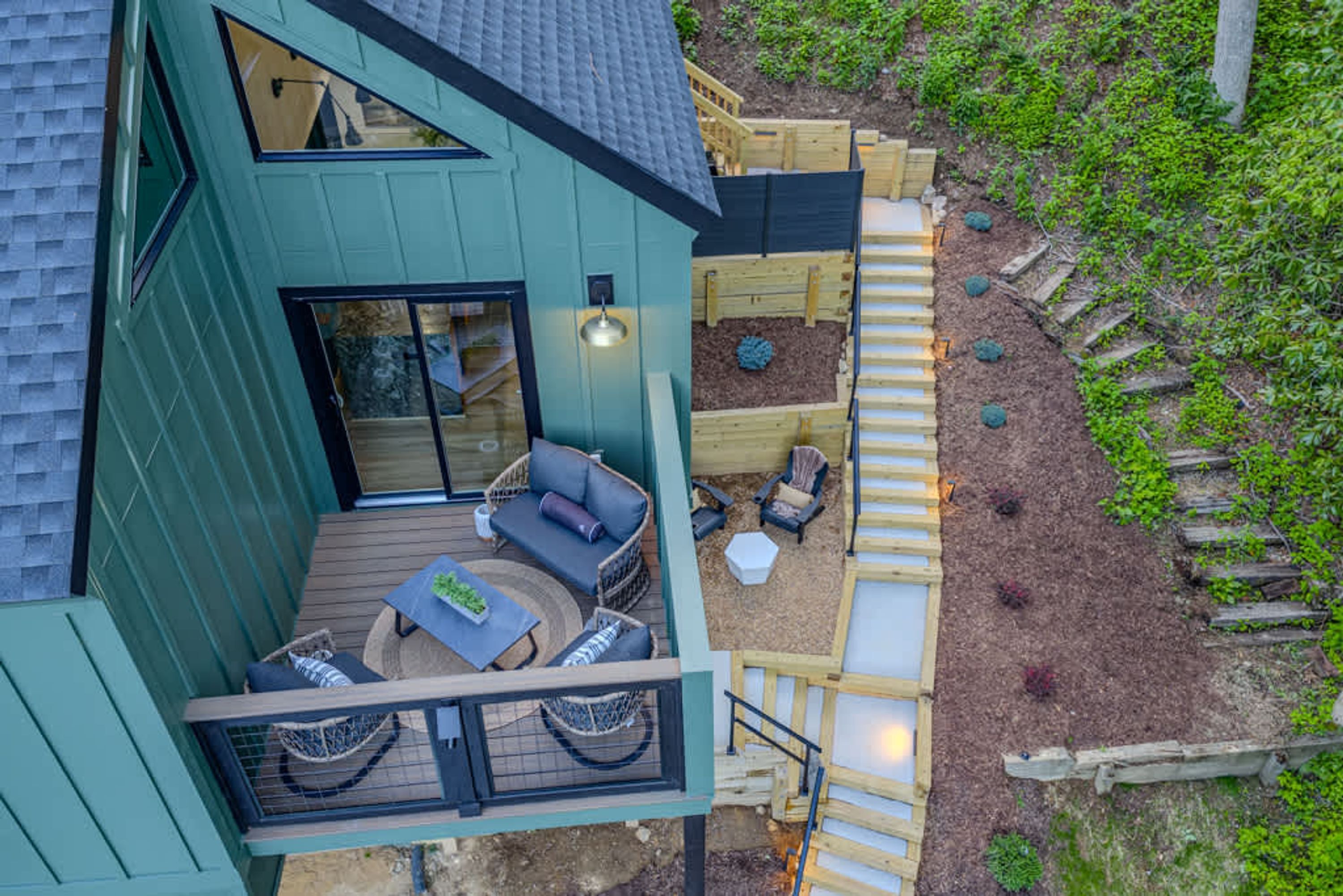 A two-story building with a deck, outdoor seating area, and a small garden.