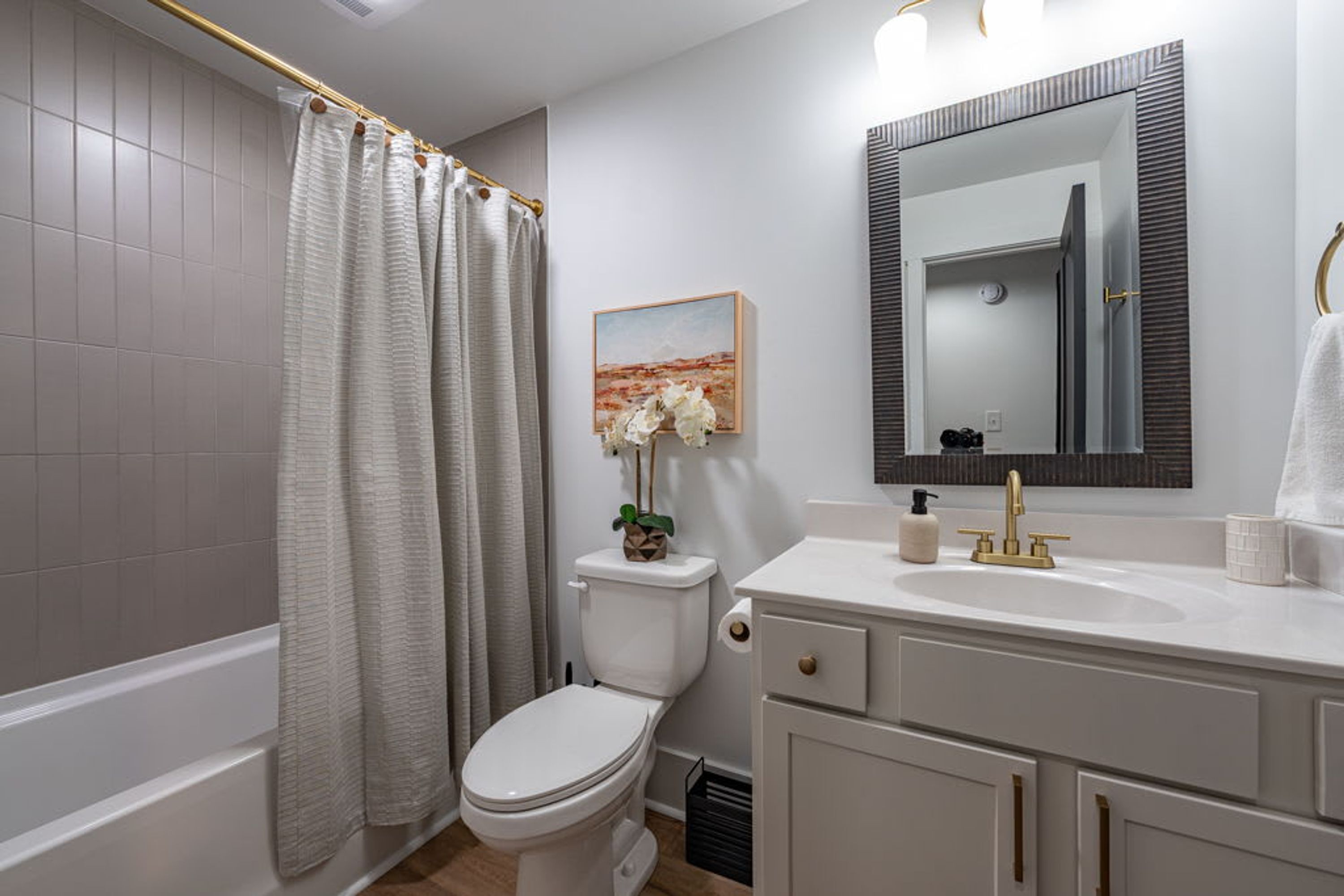 A bathroom with a bathtub, toilet, sink, and a mirror.
