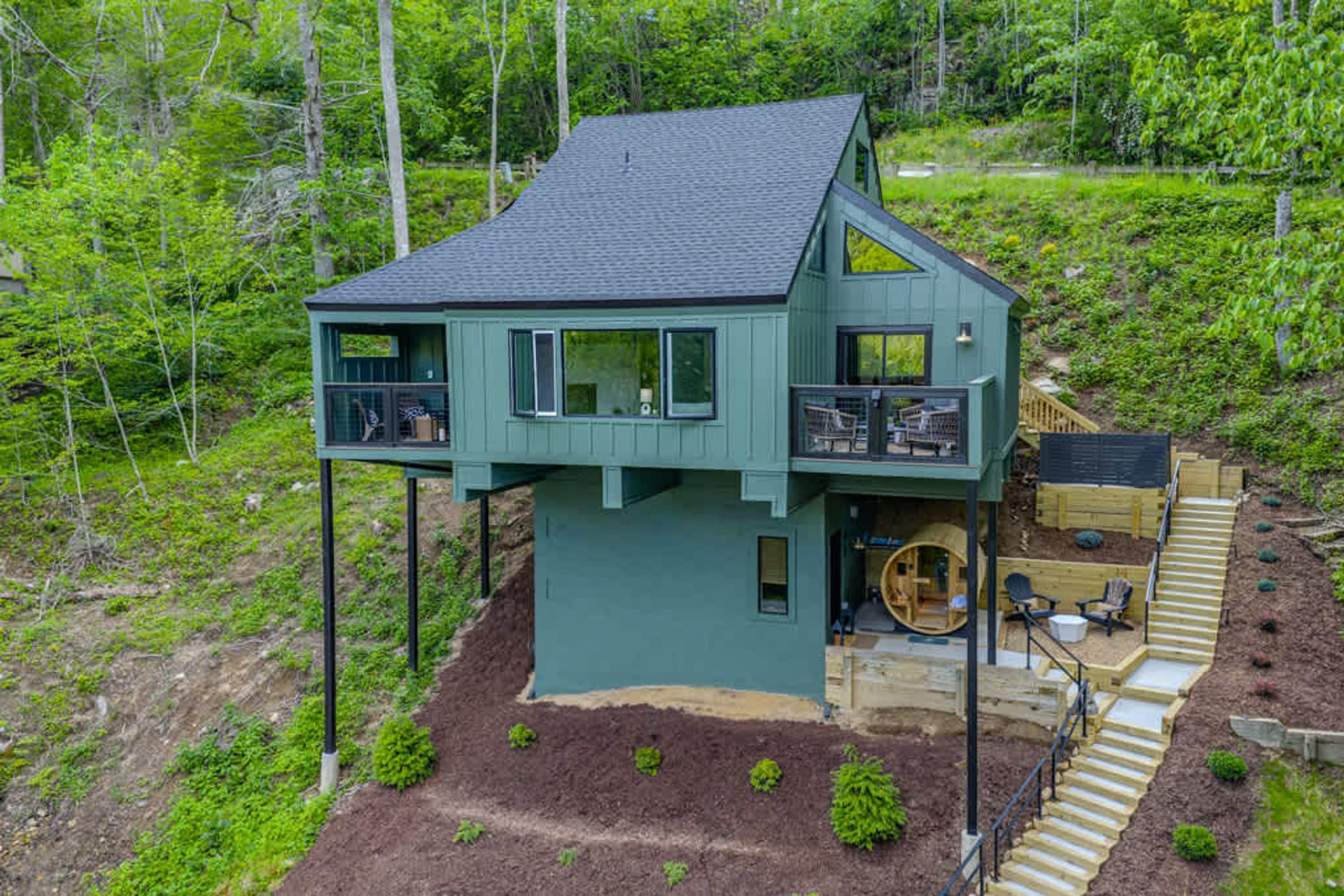 A two-story house with a balcony, a wooden deck, and a small outdoor seating area.