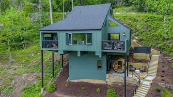 A two-story house with a balcony, a wooden deck, and a small outdoor seating area.