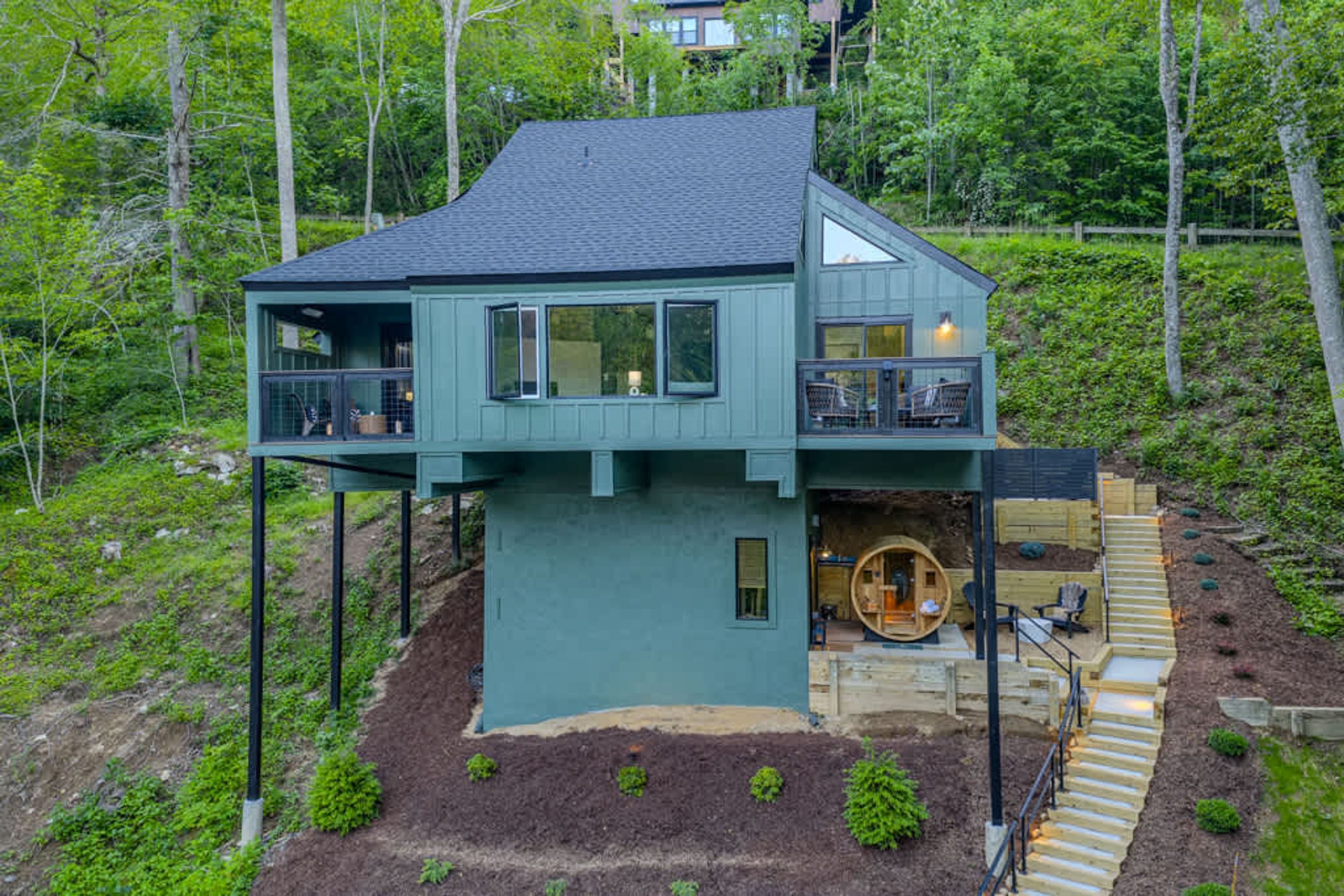 Une maison à deux étages dotée d’un balcon au niveau supérieur, d’une structure circulaire en bois à l’avant et d’un escalier menant à l’entrée.