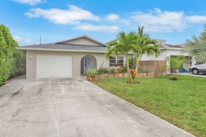 A single-story house with a garage, a front lawn, and a palm tree. - Naples Pool Home Paradise Minutes From the Beach (Naples)