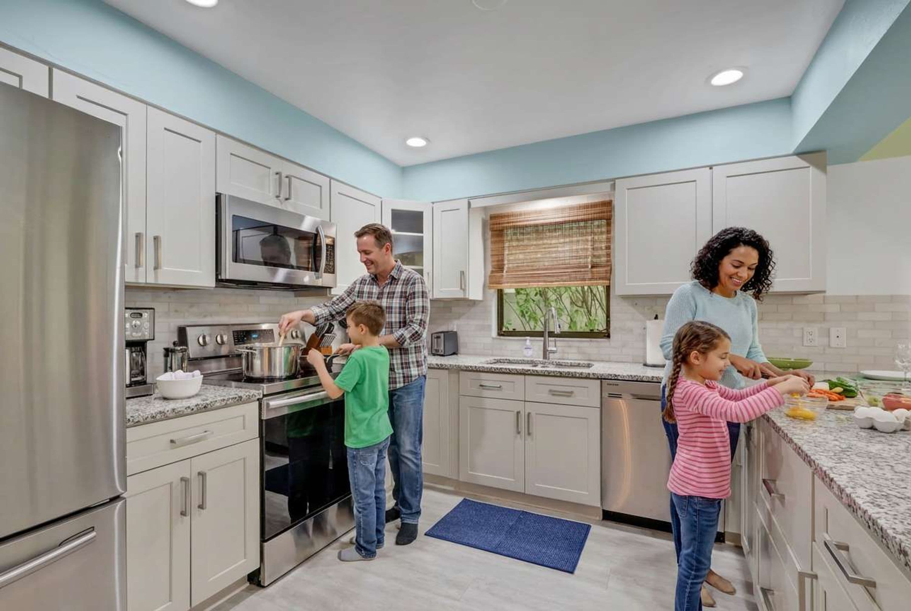 A modern kitchen with stainless steel appliances, white cabinetry, and a blue accent wall.