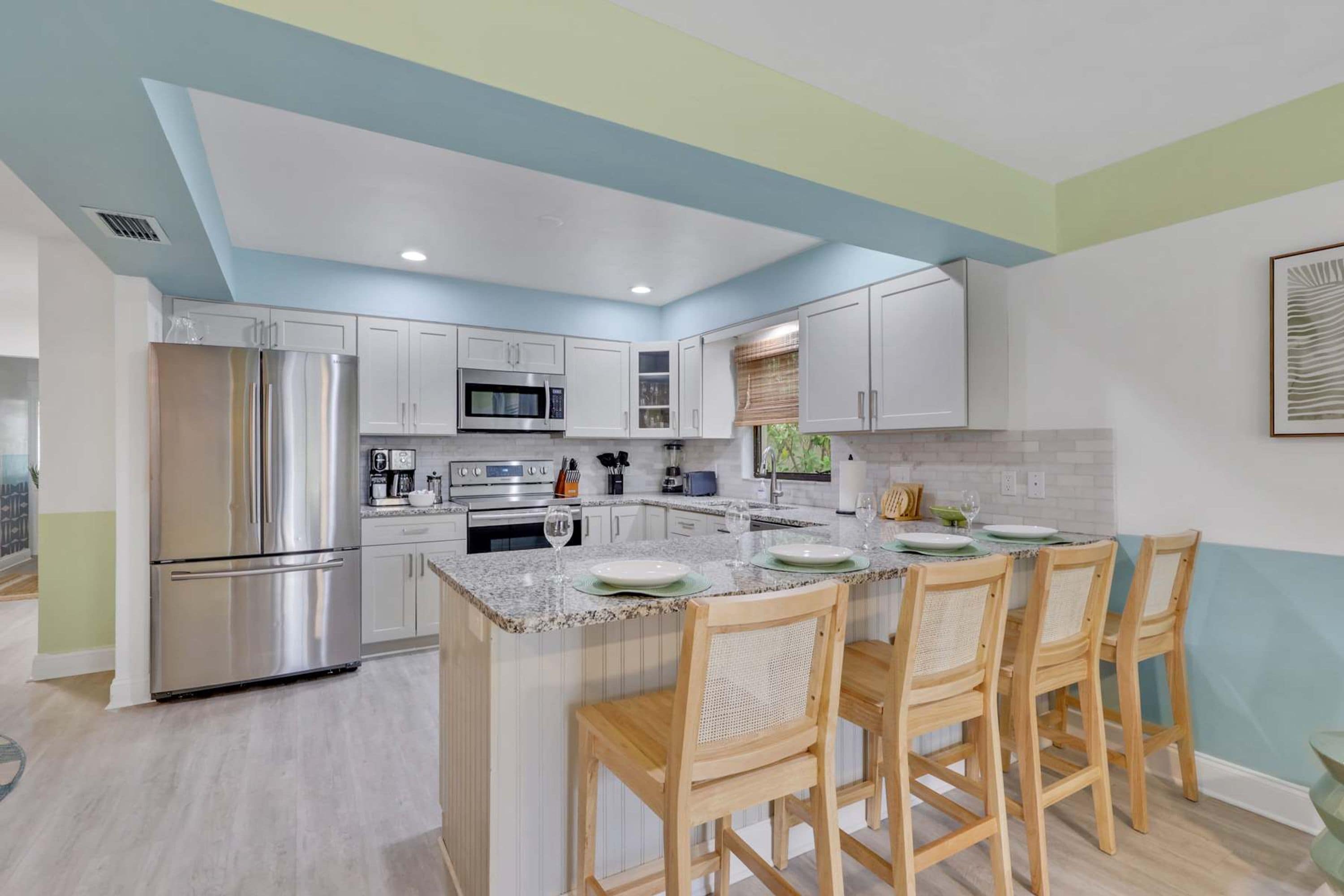 A modern kitchen with white cabinets, stainless steel appliances, and a granite countertop.
