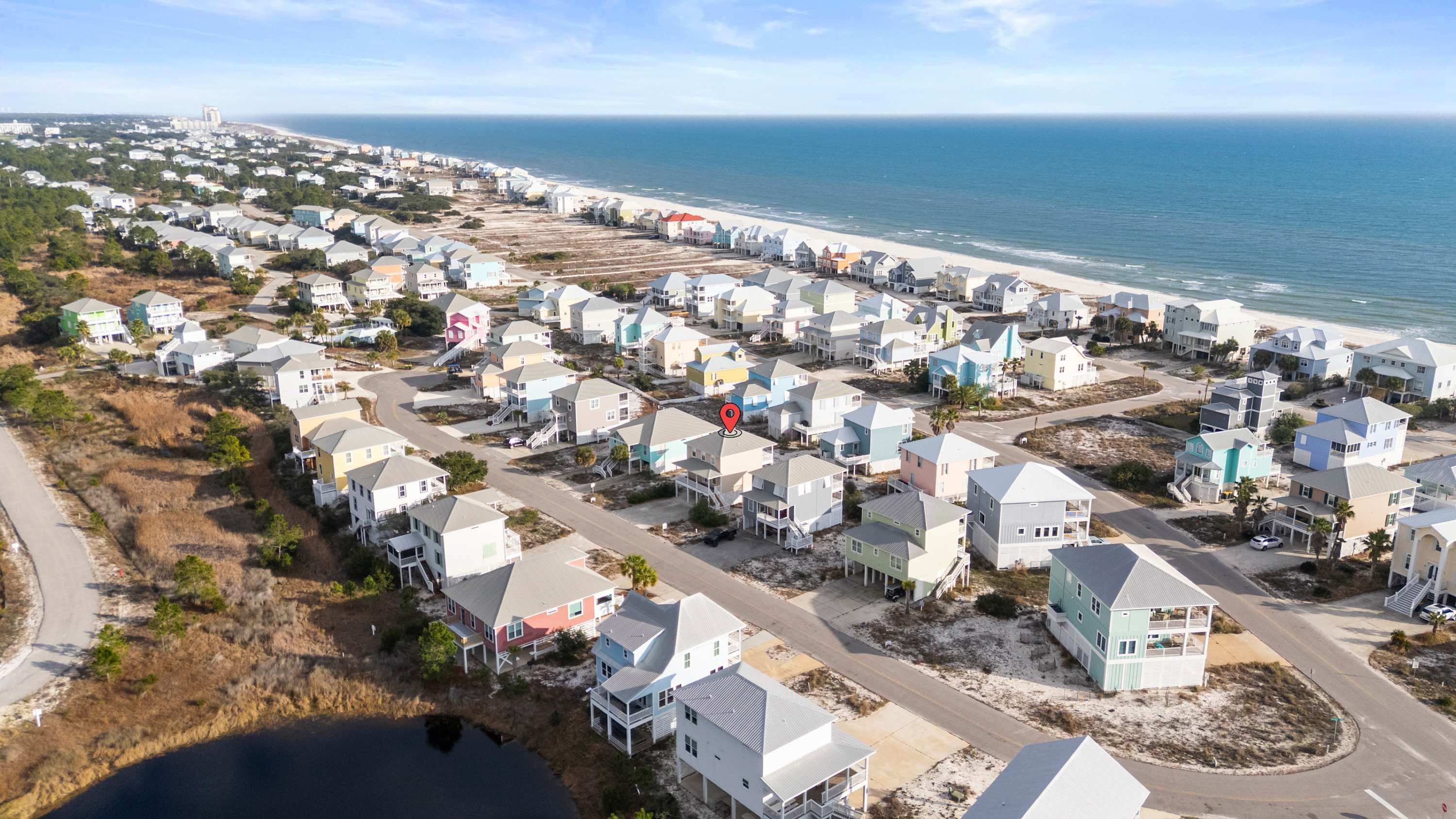 Une zone résidentielle côtière avec des maisons, une plage et un ciel dégagé.