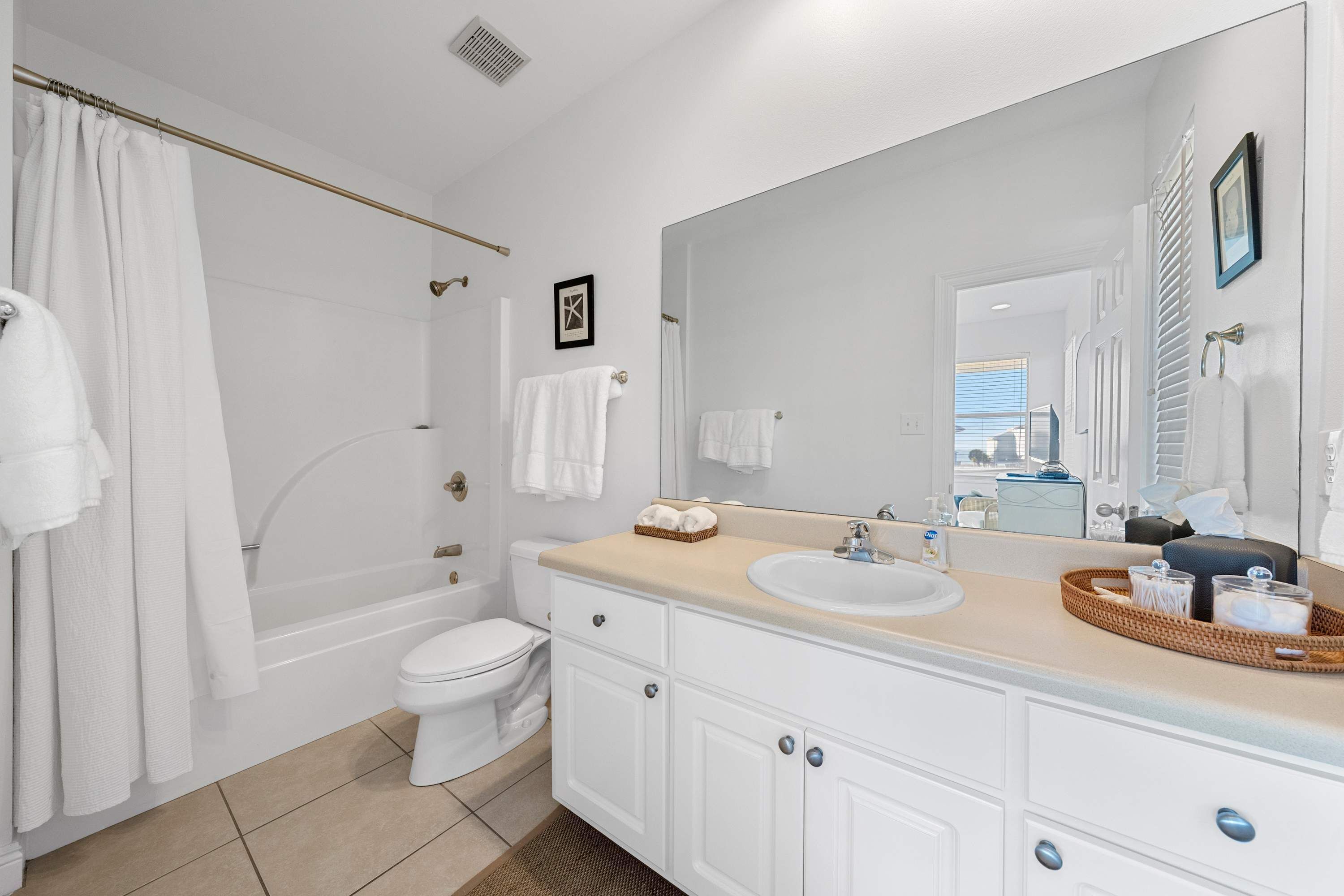 A bathroom with a bathtub, toilet, sink, and a large mirror.