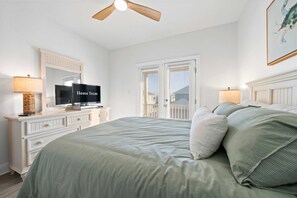 Un dormitorio con cama, cómoda, televisor y ventilador de techo.