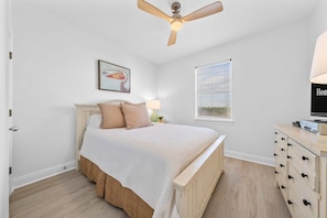 A bedroom with a bed, a ceiling fan, a window with blinds, a painting, and a dresser with drawers. - Bella Vacanza Minutes to Beach Community Pool (Gulf Shores)