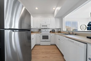 A modern kitchen with white cabinetry, stainless steel appliances, and a wooden floor. - Bella Vacanza Minutes to Beach Community Pool (Gulf Shores)