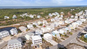 A coastal residential area with multiple two-story houses, a road, and a body of water in the background. - Bella Vacanza Minutes to Beach Community Pool (Gulf Shores)