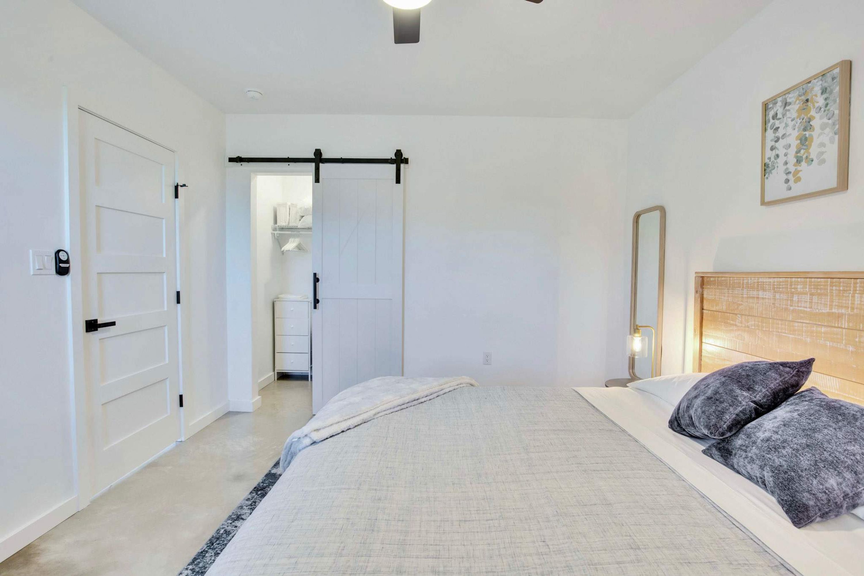 A bedroom with a bed, bedside table, and a door leading to a bathroom.