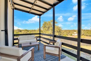 A covered outdoor seating area with a view of a natural landscape. - Hill Country Hideaway Modern Barndominium for 6 (Dripping Springs)