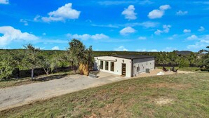 A single-story building with a flat roof, a fenced yard, and a clear sky. - Hill Country Hideaway Modern Barndominium for 6 (Dripping Springs)