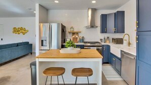 A modern kitchen with a central island, stainless steel appliances, and blue cabinetry. - Hill Country Hideaway Modern Barndominium for 6 (Dripping Springs)