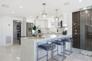 A modern kitchen with a central island, stainless steel appliances, and a glass backsplash. - Waterfront Heated Pool Home Gym Fire Pit (Tampa)